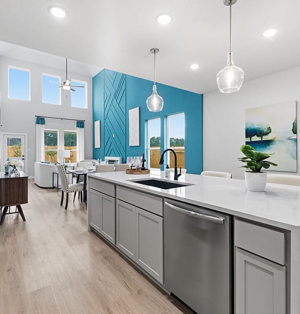 Open-concept kitchen in a First America Homes model at Valley Ranch, with a white quartz island, pendant lights and gray cabinets